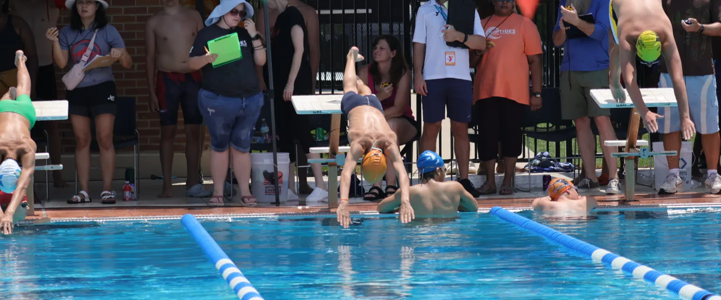 person diving into pool at swim meet