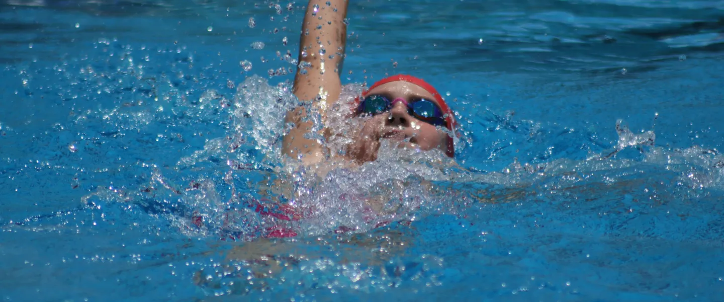 young swimmer in pool doing backstroke